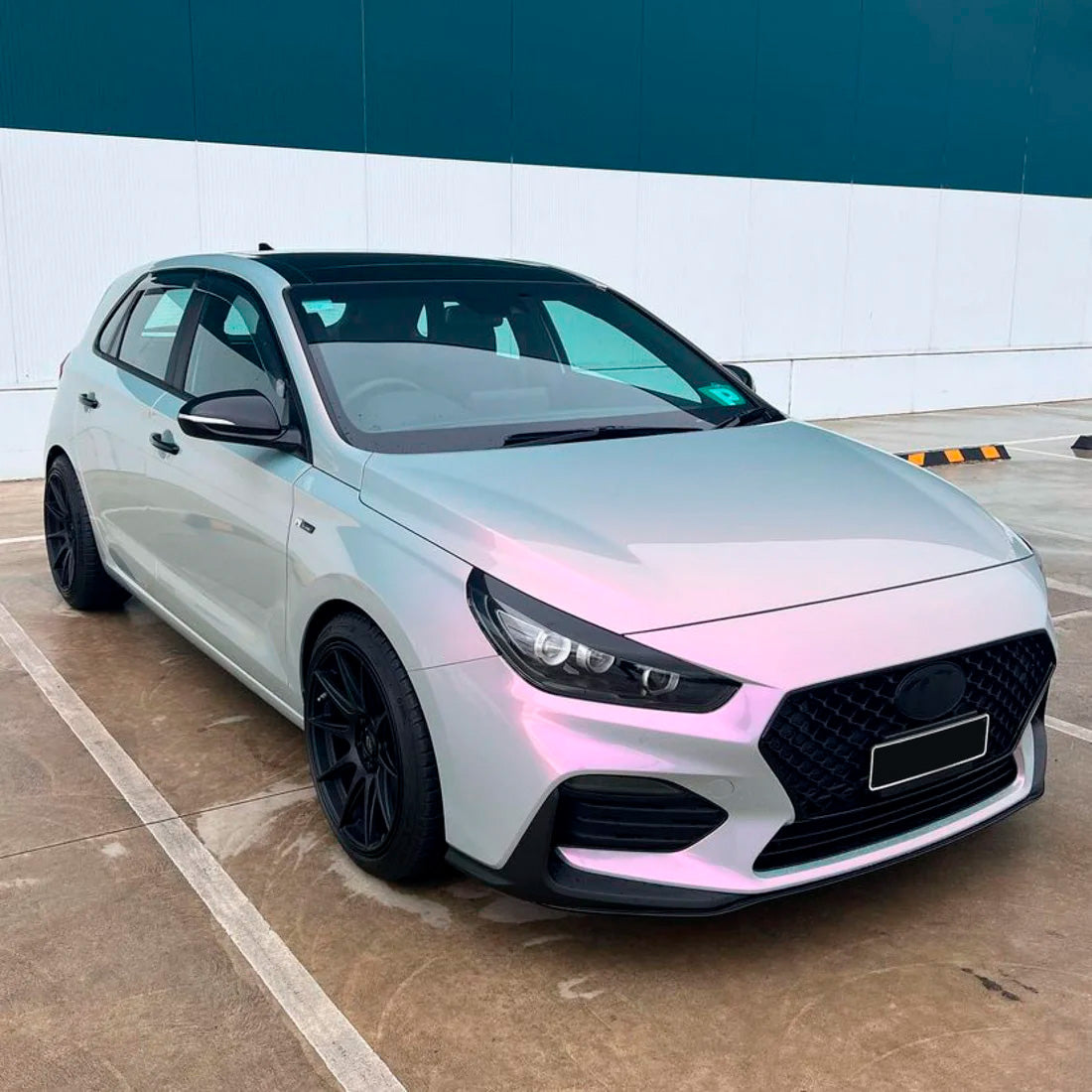 Sleek hatchback wrapped in glossy Silver Sunset vinyl, showcasing subtle shifts from silver to pink, enhancing the vehicle's sporty, modern aesthetic.