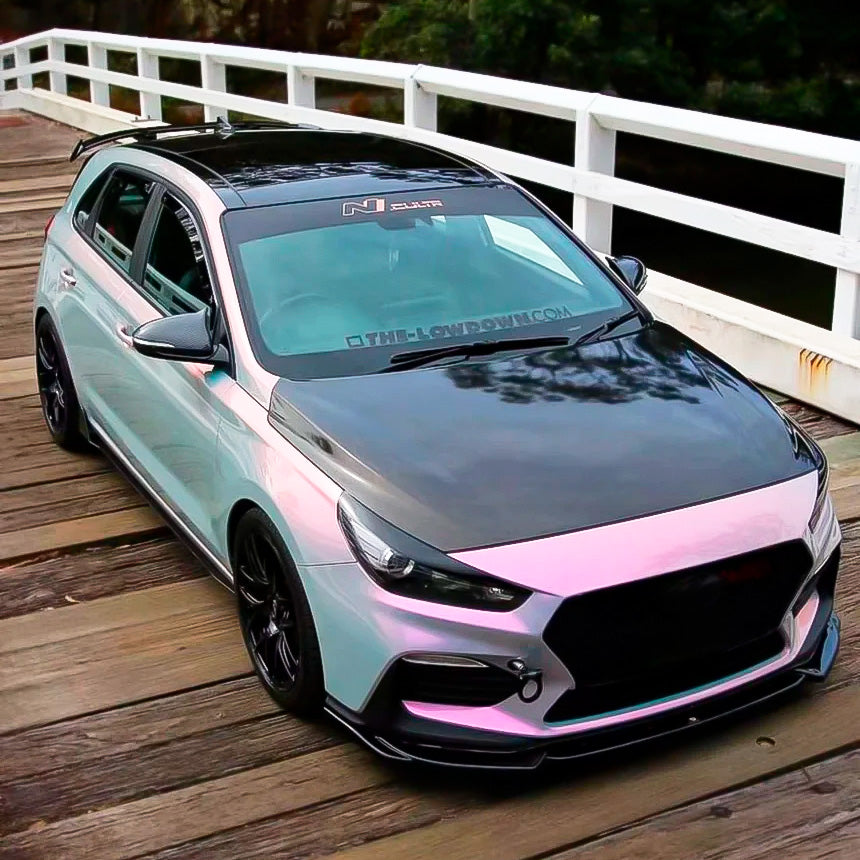 Sporty hatchback featuring glossy Silver Sunset vinyl wrap, beautifully capturing dynamic pink-to-silver color shifts, complemented by a sleek carbon fiber hood.