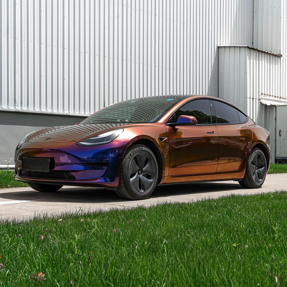 Tesla Model 3 fully wrapped in TeckWrap Purple Sunset (RD20PRO-HD) gloss chameleon vinyl showing vivid orange and blue hues.