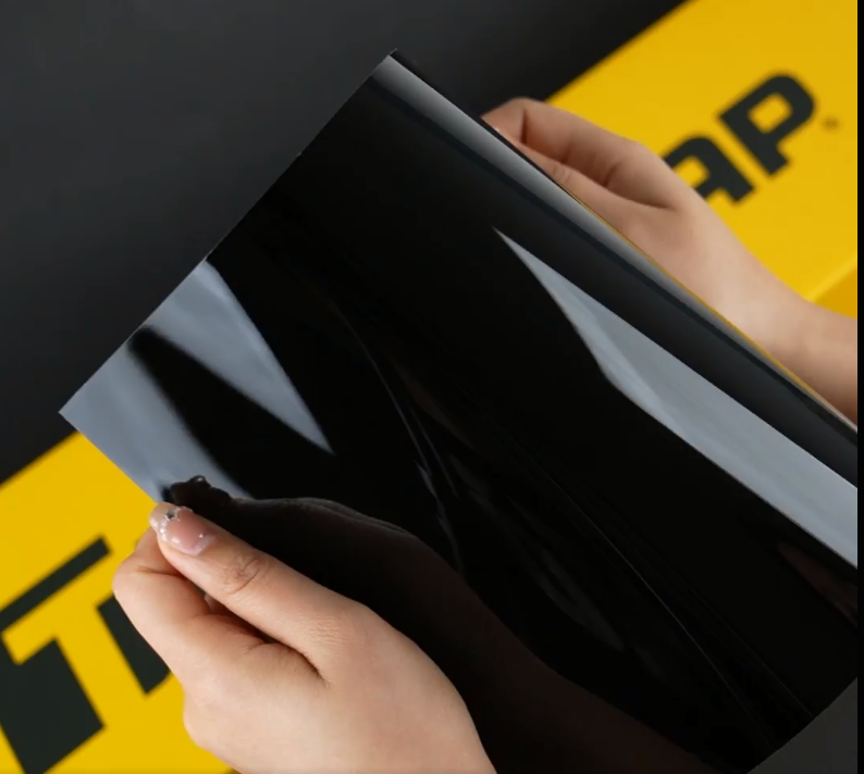 Hands showing A4 Sample of BLK X Jet Black TeckWrap Paint Protection Film