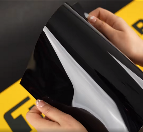 Hands showing A4 Sample of Black Phantom TeckWrap Paint Protection Film