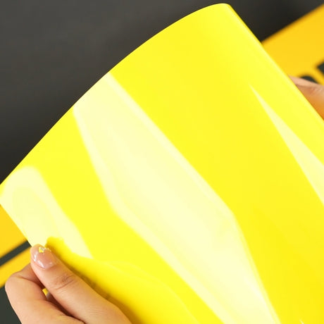 Close-up of TeckWrap Louvre Yellow (CG43-HD) Gloss Vinyl Wrap held by hand, highlighting its glossy, bright yellow hue