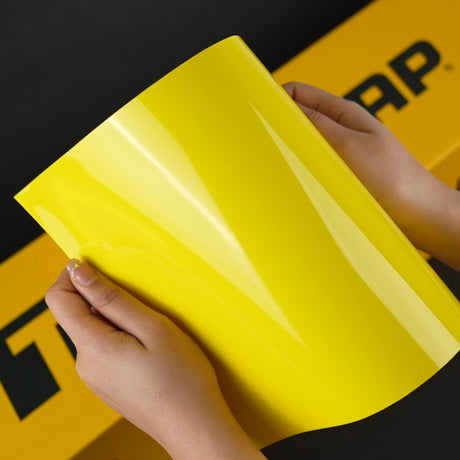Close-up of TeckWrap Louvre Yellow (CG43-HD) Gloss Vinyl Wrap held by hand, highlighting its glossy, bright yellow hue
