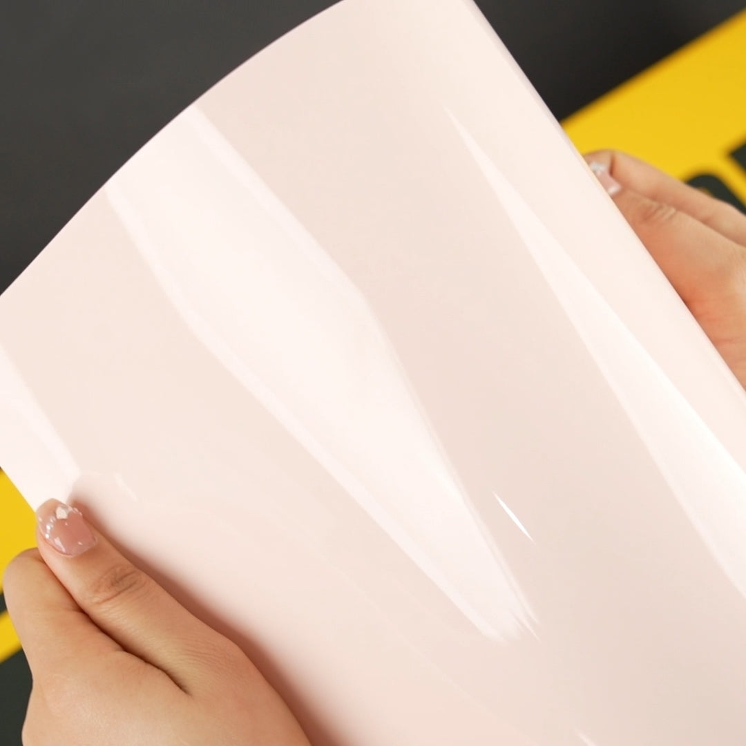 Hands holding TeckWrap CG50-HD Strawberry Milk gloss vinyl wrap showing light reflection and flexibility