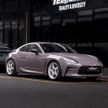 Subaru BRZ wrapped in TeckWrap Wild Dove (CG55-HD) Gloss Vinyl, featuring a smooth, high-gloss grey finish with white wheels, parked in front of a TeckWrap showroom — perfect for high-end automotive wrap showcases.