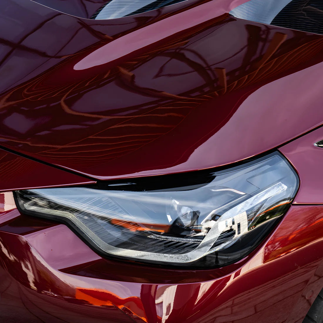 Close-up of a glossy dark red vinyl wrap BMW