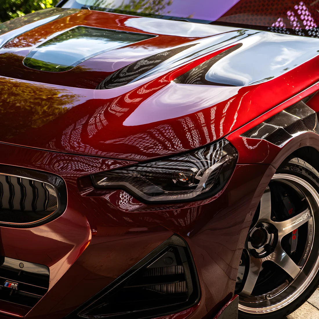 Close-up of a glossy dark red vinyl wrap sports car