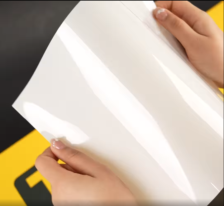 Hands showing A4 Sample of E75 Crystal TeckWrap Paint Protection Film