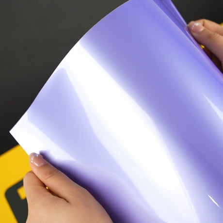 Hands displaying the TeckWrap SL07-HD Royal Purple vinyl wrap A4 sample, featuring a sleek, high-gloss lavender finish with a bold, reflective sheen—perfect for showcasing vivid color and smooth application.