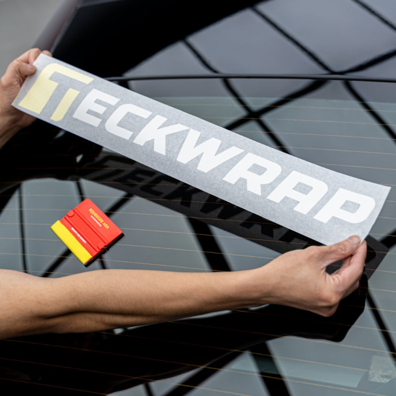 TeckWrap logo sticker being positioned on rear windshield with red squeegee tool