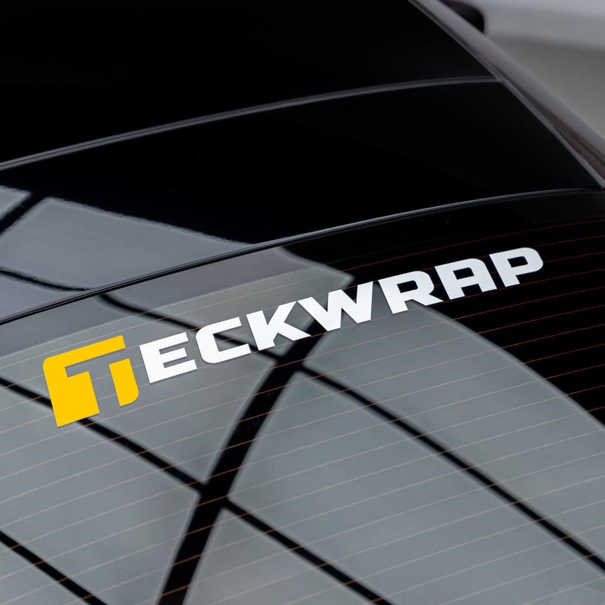 Close-up of TeckWrap vinyl logo sticker fully applied to back window of a vehicle