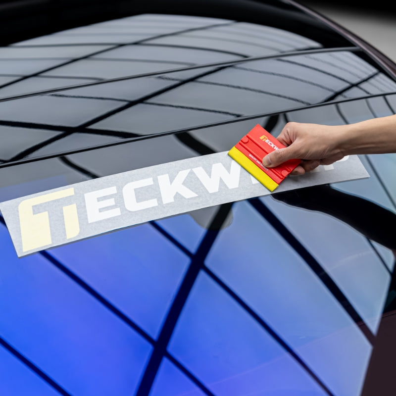 Squeegee tool applying TeckWrap vinyl logo decal on vehicle's rear windshield