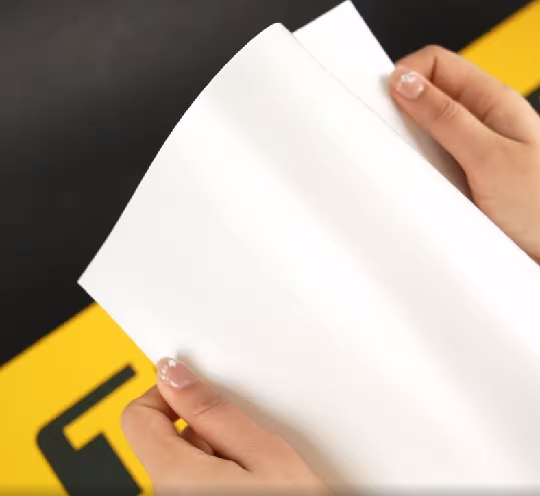 Hands showing A4 Sample of X75m Shade TeckWrap Paint Protection Film