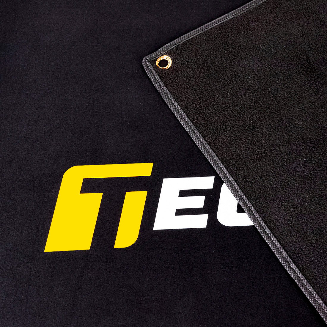 Close-up view of TeckWrap branded black banner corner with reinforced grommet and stitched edge for secure mounting