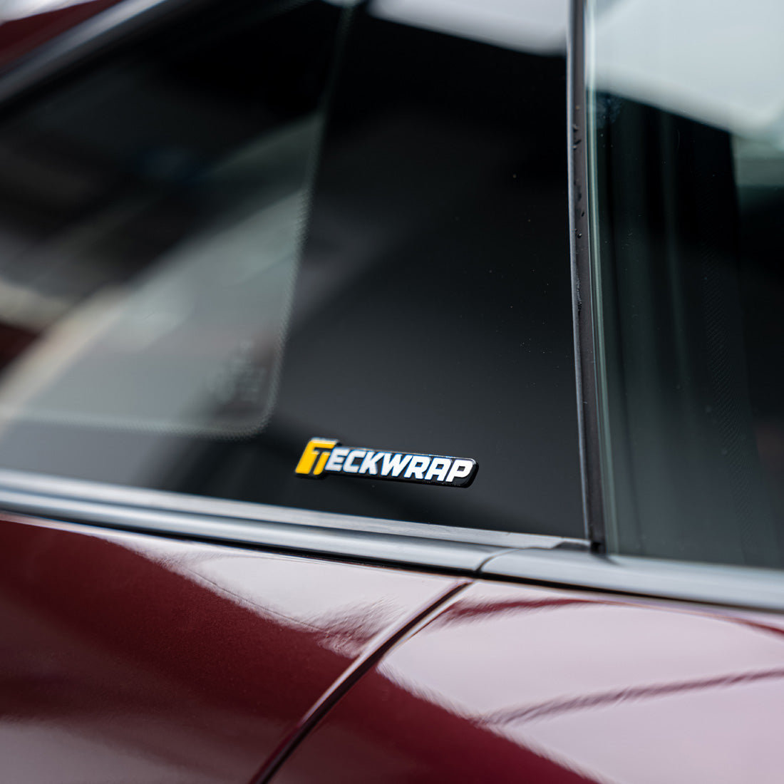 TeckWrap 8cm logo sticker displayed on rear triangle window for automotive branding.