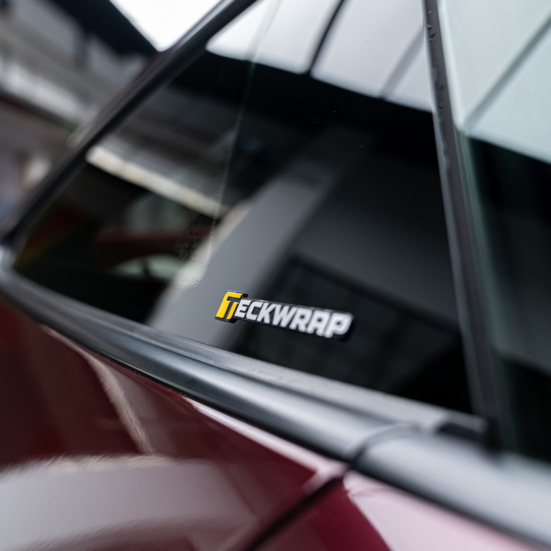 Close-up of TeckWrap vinyl logo sticker on passenger side window of a vehicle.