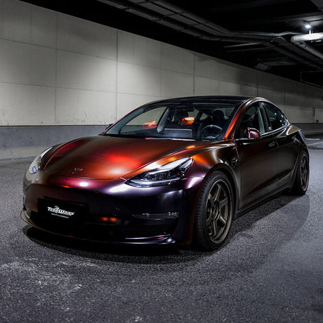 Tesla Model 3 wrapped in TeckWrap Madeira Red Matte vinyl, parked under tunnel lights revealing its chameleon red-purple tones.