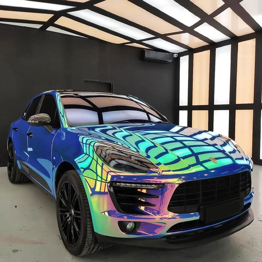 Porsche Macan in TeckWrap Frozen Berry (MCH08) chrome wrap, glowing in gradient blue, aqua, and purple iridescent tones under showroom light