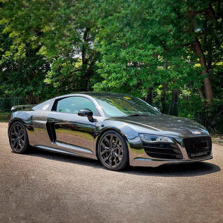Audi R8 wrapped in Jet Black (CHM10-HD) Chrome Vinyl, displaying a stunning, mirror-like reflective surface under natural daylight.