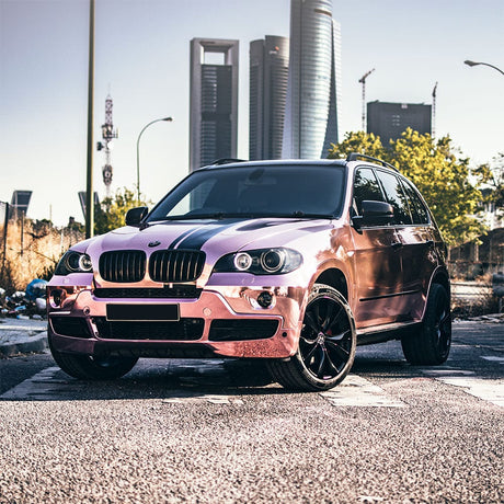 BMW SUV wrapped in eye-catching TeckWrap Rose Gold (CHM03-HD) Chrome Vinyl, featuring a bold reflective finish under sunlight in an urban backdrop.