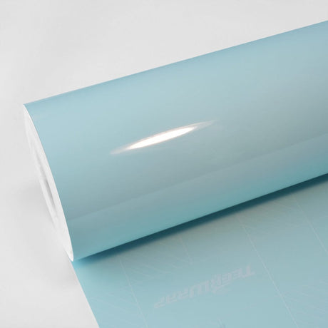 Glossy light blue vinyl wrap roll partially unrolled on a white surface, showing the smooth high-gloss finish – TeckWrap Bali Blue CG37-HD