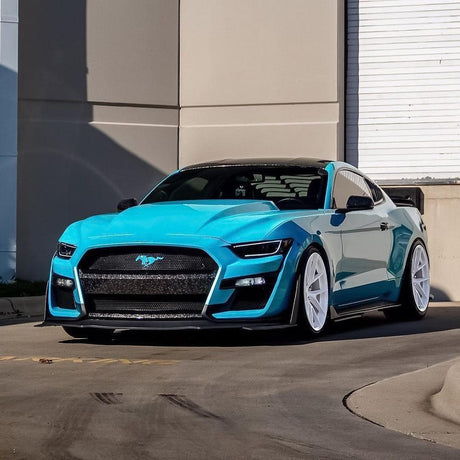 Sleek sports car wrapped in Teckwrap Gloss Caribbean Blue (RB09-HD), highlighting its striking color depth and glossy reflective finish in an urban setting.