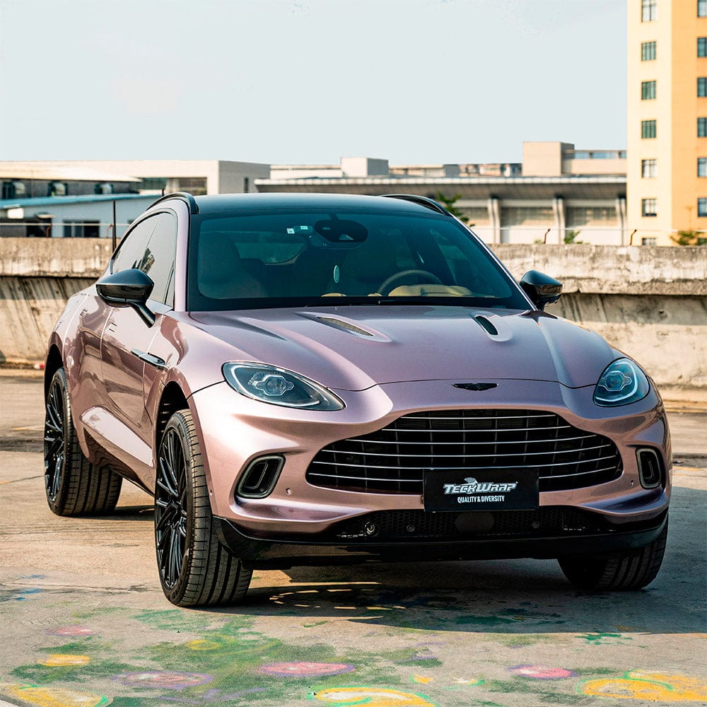 Front view of an Aston Martin SUV featuring TeckWrap Copper Bronze (HM15-HD) Gloss Vinyl Wrap, capturing its luxurious metallic sheen in natural sunlight.