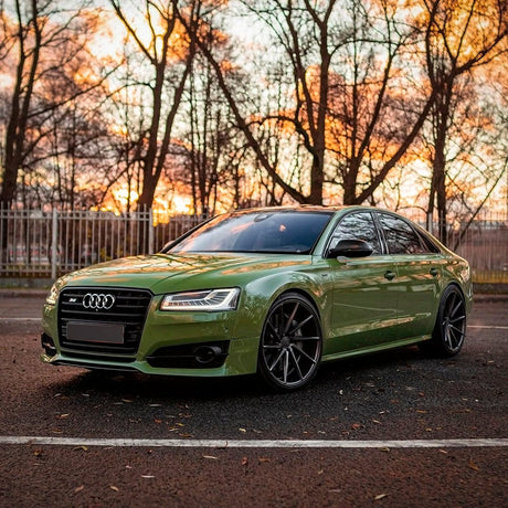 Luxury Audi wrapped in TeckWrap French Olive (CG31-HD) Gloss Vinyl, highlighting the sophisticated, natural green hue under a sunset background.