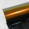 Close-up of TeckWrap Honey Lime (RD12-HD) glossy vinyl wrap roll showcasing its vibrant gold-to-green color shift, reflecting a luxurious metallic sheen.