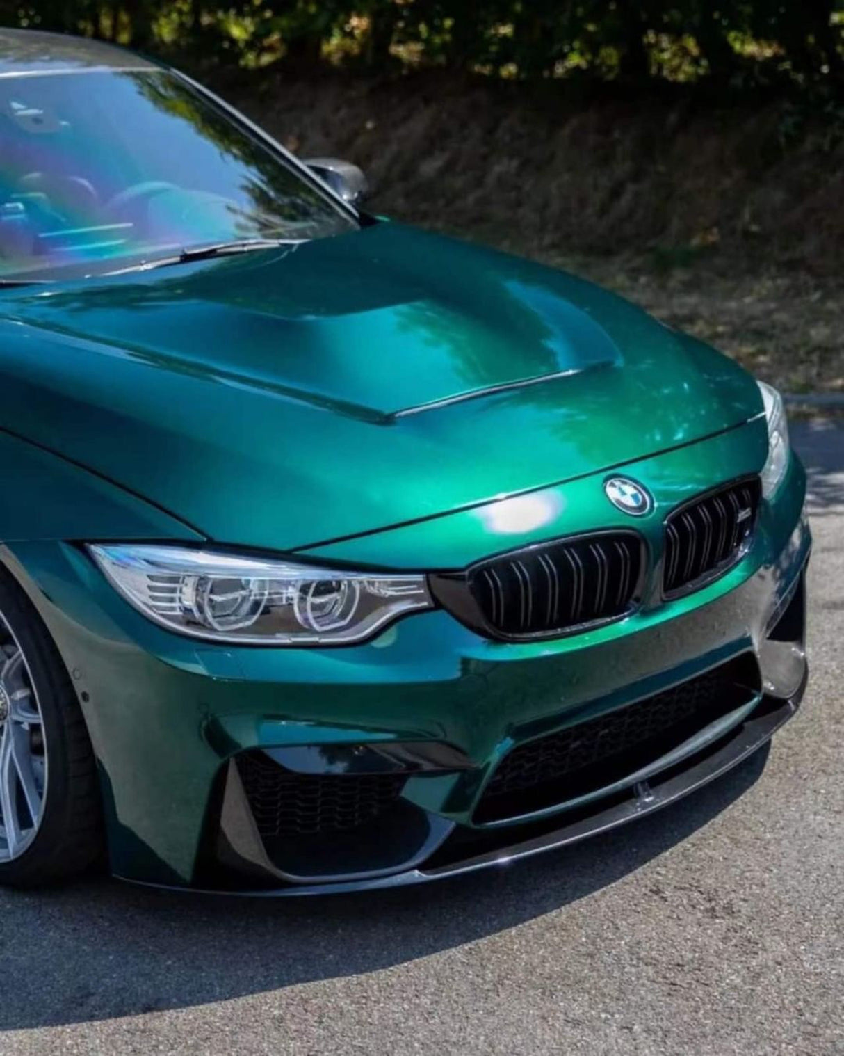 Front angle view of a BMW sedan in TeckWrap Hunter Green (GAL29-HD) glossy wrap, capturing the luxurious gloss and intense green hue.