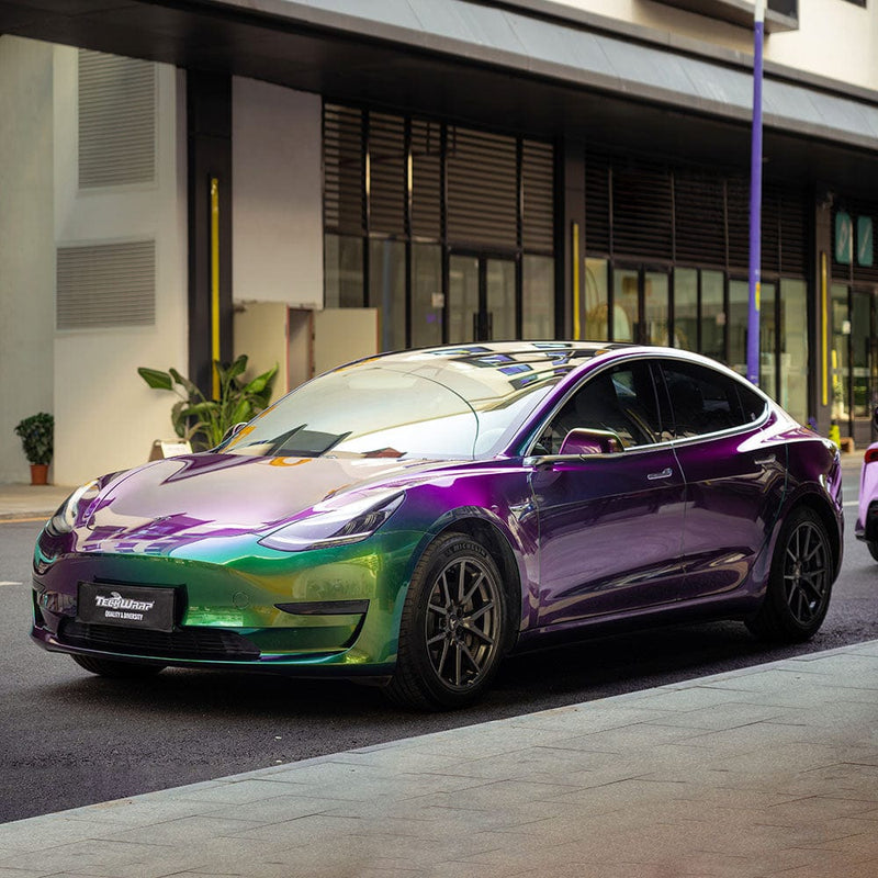 Tesla elegantly wrapped in TeckWrap Iridescent Green vinyl, displaying an eye-catching gradient of green and purple shades under natural lighting.