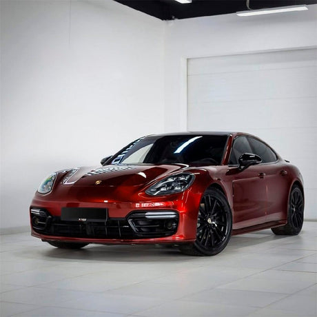 Front-angle view of a sleek Porsche luxury sedan fully wrapped in Supreme Red Gloss Metallic Vinyl (GAL26-HD), illustrating the wrap’s stunning reflective depth, rich metallic finish, and premium aesthetic that enhances the vehicle’s sporty appearance.