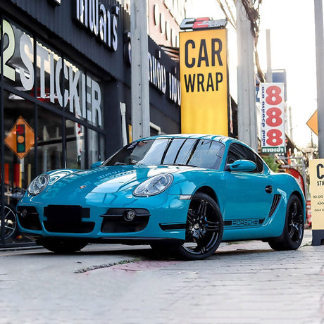 Porsche Cayman wrapped in TeckWrap Rolling Sea (CG21-HD) Gloss Vinyl, delivering a striking, reflective blue appearance — a sporty, eye-catching color for custom automotive styling with a luxurious finish.