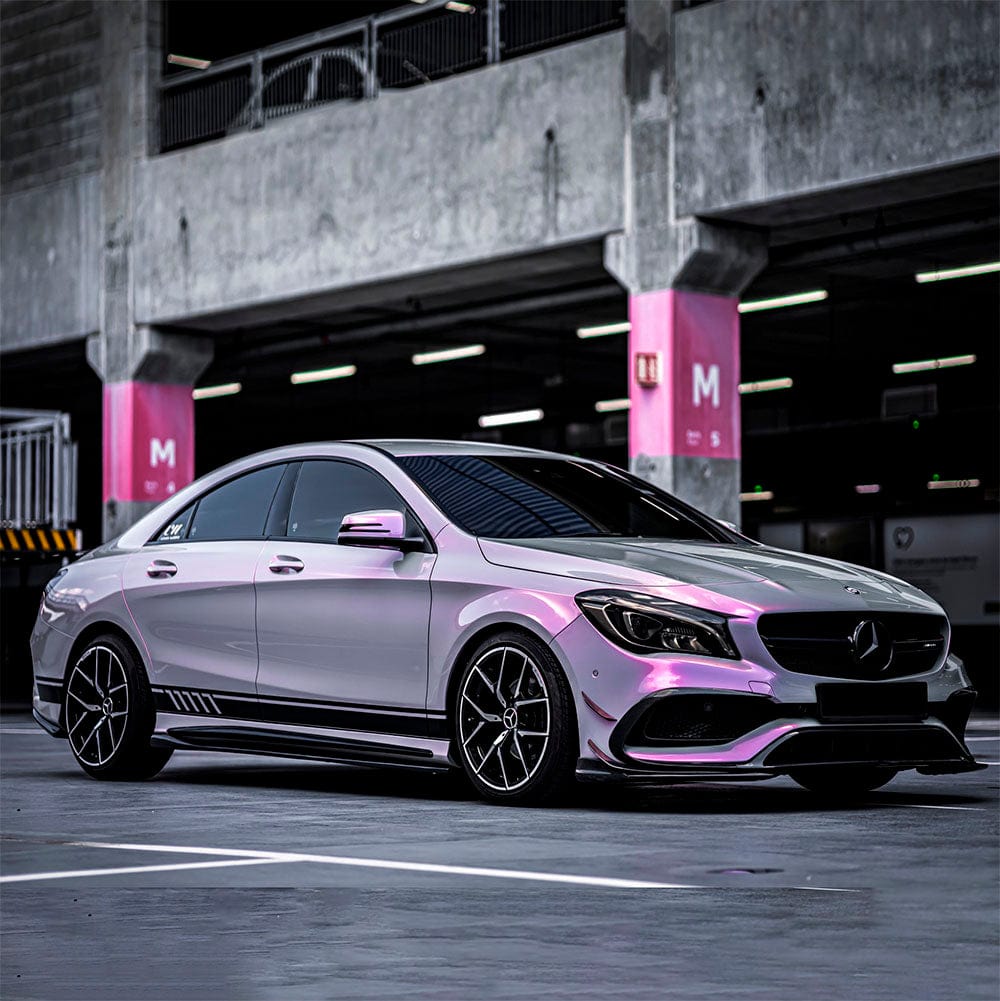 Stylish Mercedes-Benz sedan enhanced by glossy Silver Sunset vinyl wrap, elegantly reflecting vibrant hues of pink and silver under indoor lighting.