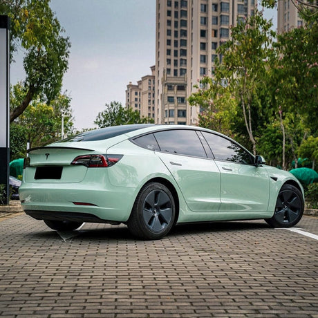 Tesla wrapped in TeckWrap Monsoon Green High Gloss Vinyl Wrap (CG39-HD), parked outdoors demonstrating the sleek, modern aesthetic of this pastel green shade.