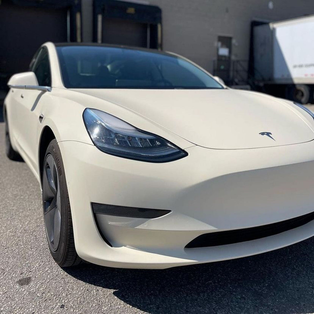 Detailed close-up of Tesla Model 3's hood wrapped in Vanilla Cream (SCM26-R) Matte Vinyl, highlighting its smooth, subtle texture