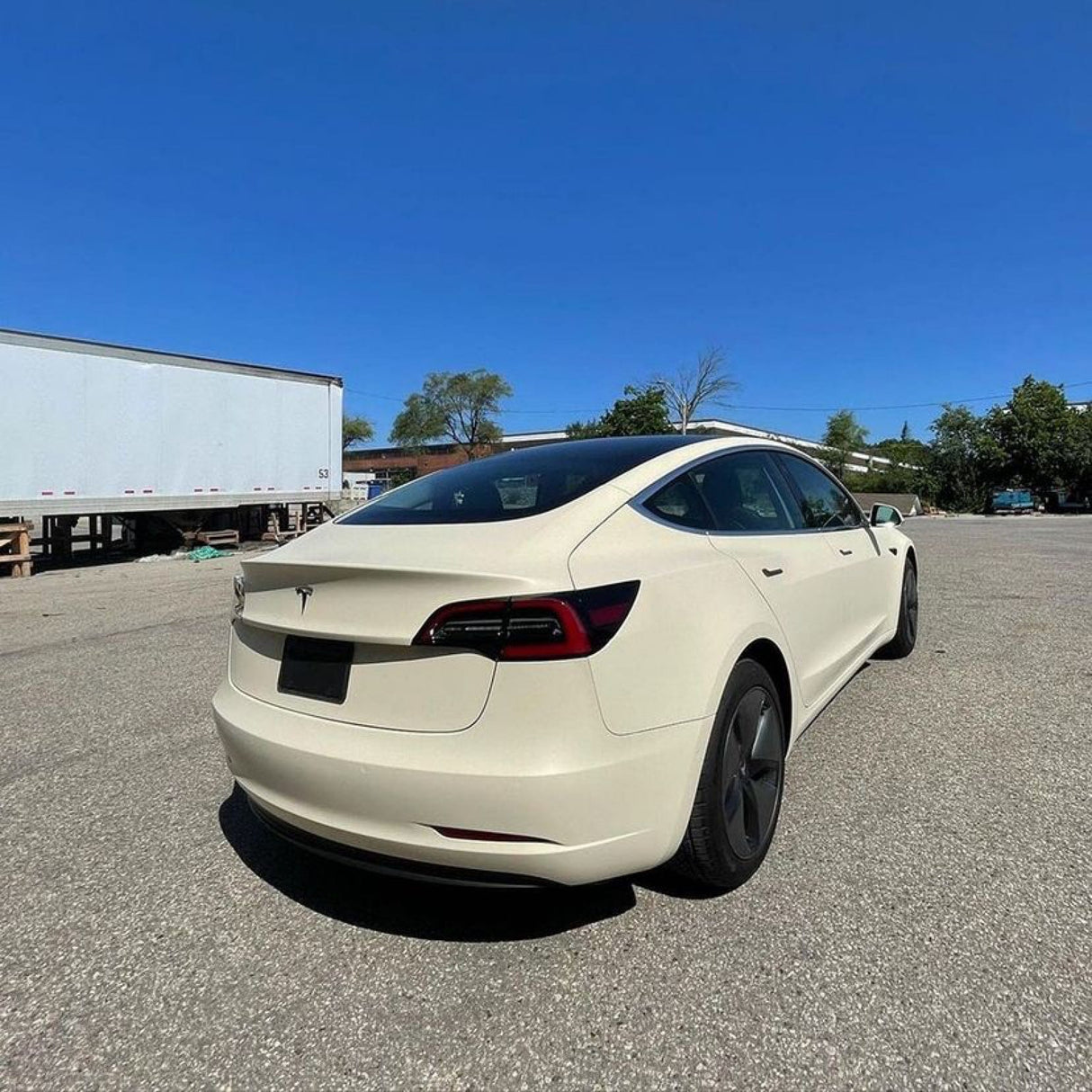 Rear-angle shot of Tesla Model 3 wrapped in Vanilla Cream (SCM26-R) Matte Vinyl, illustrating a pristine and elegant finish by TeckWrap