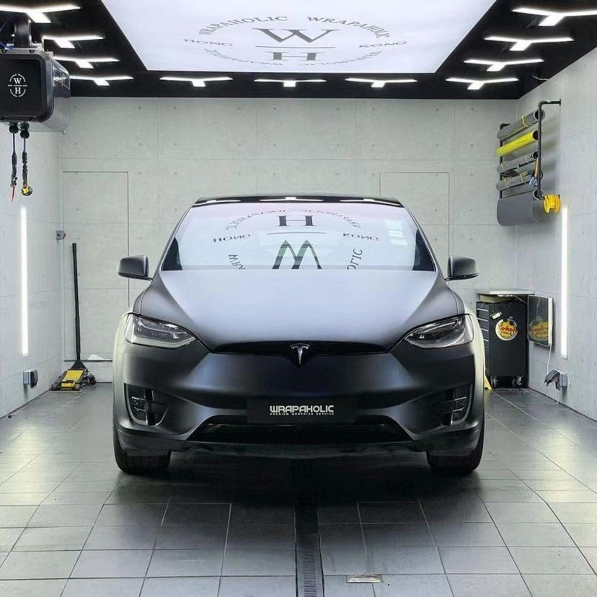Front view of a Tesla wrapped elegantly in TeckWrap Satin Boysenberry Black (SMT04), displayed under professional lighting