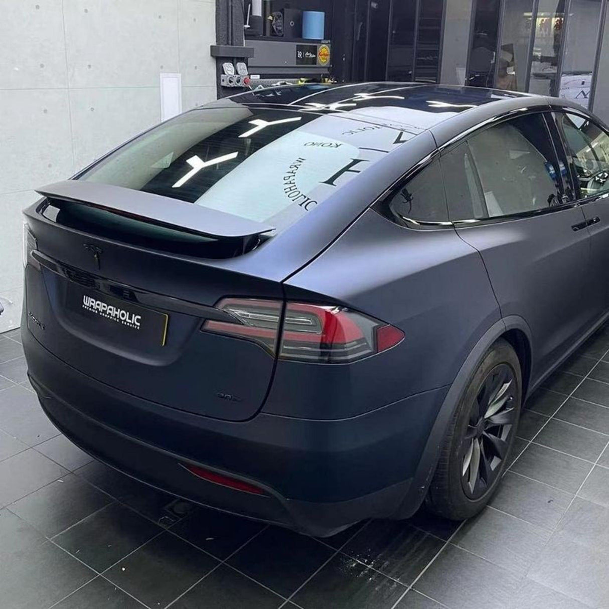 Rear and side view of Tesla car wrapped in premium TeckWrap Satin Boysenberry Black (SMT04) vinyl, emphasizing smooth contours and deep satin color