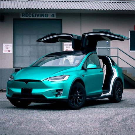 Front angle of a Tesla Model X wrapped in TeckWrap Emerald Green Satin Vinyl, doors open showcasing the dynamic satin hue.