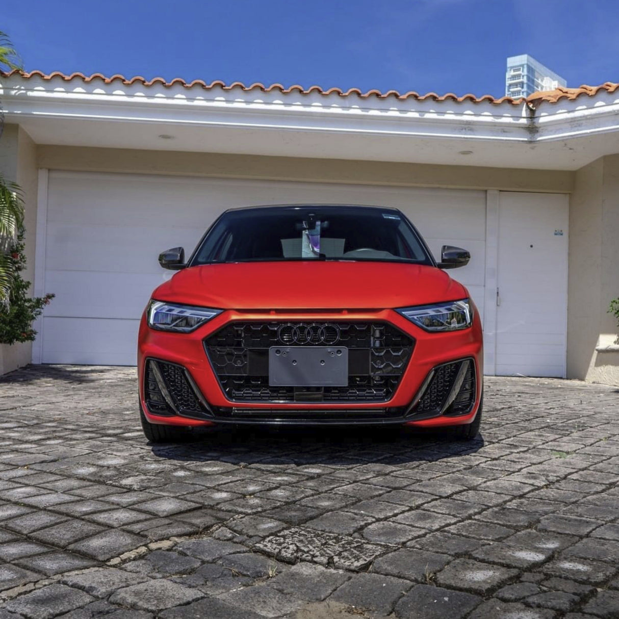 Audi vehicle fully wrapped in TeckWrap Flame Red SMT15 satin vinyl parked in front of a garage under bright sunlight.