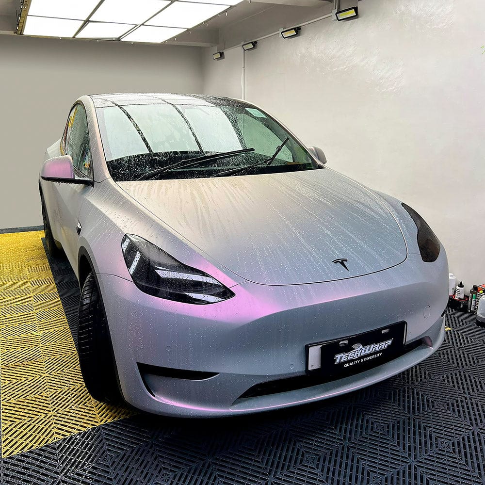 Front view of Tesla covered in TeckWrap Silver Sunset Matte Satin Vinyl Wrap, capturing the stylish matte surface with raindrops accentuating its unique silver and pink gradient effect.