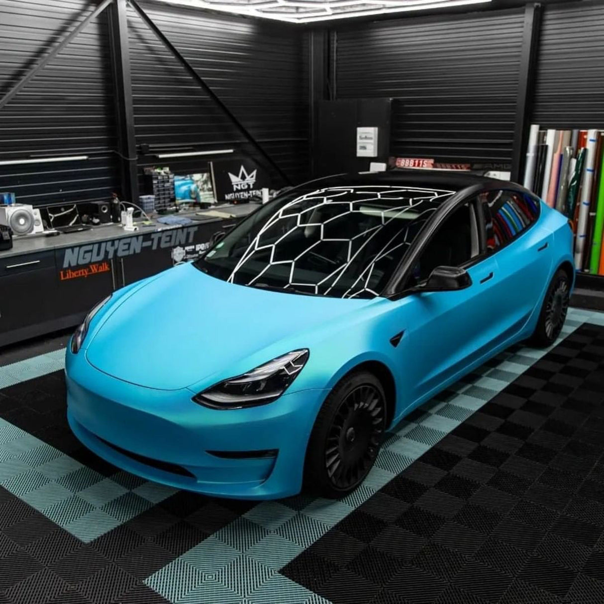 Elevated Perspective of Tesla Model 3 Wrapped in TeckWrap Surf Blue (SMT11) Satin Vinyl in a Workshop Setting, Emphasizing the Wrap's Premium Quality and Vibrant Appearance