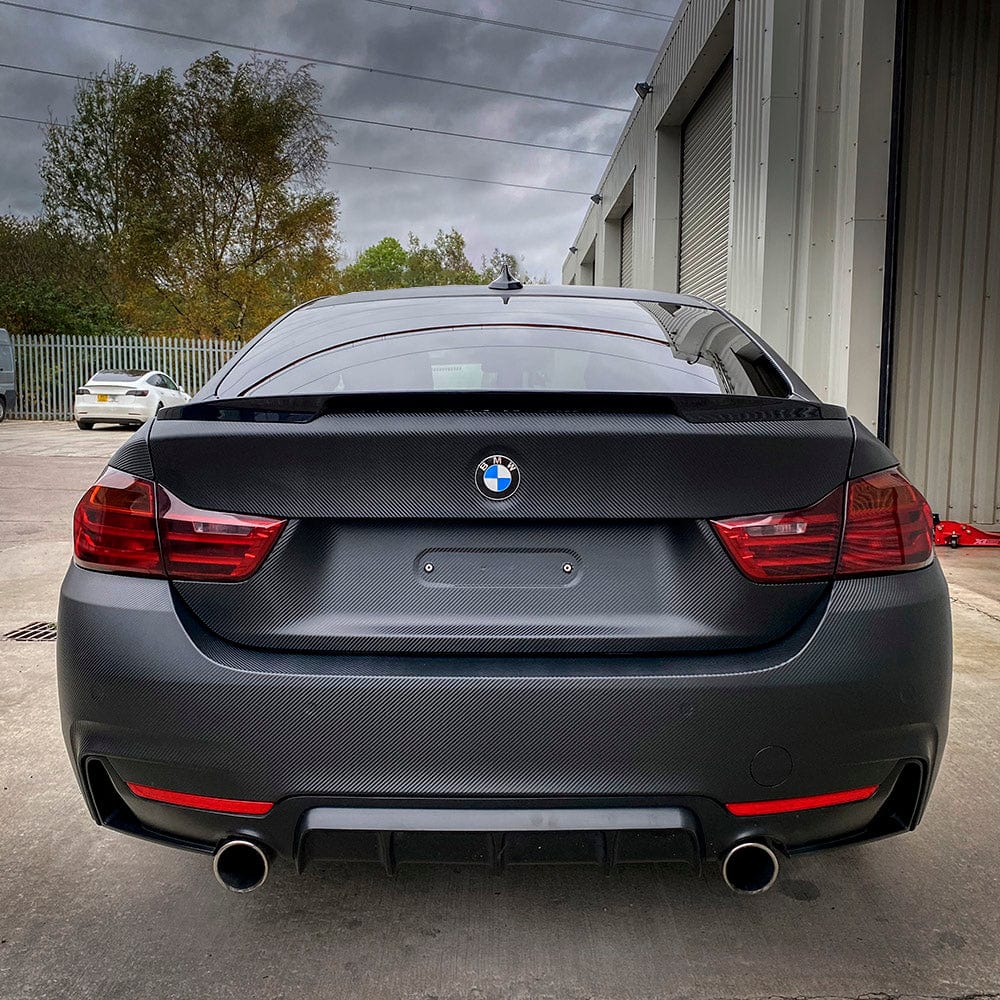 Rear view of BMW showcasing trunk wrapped in Noir Black Carbon (CF01) Vinyl Wrap by TeckWrap, enhancing the vehicle's sporty and luxurious appearance.