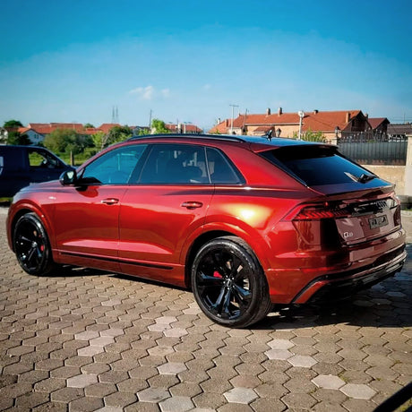 Rear-side angle of the Audi Q8 showcasing the Supreme Red Gloss Metallic Vinyl Wrap (GAL26-HD) by TeckWrap, capturing the vibrant red tone, exceptional metallic reflection under sunlight, and the wrap’s seamless application on the vehicle’s body, emphasizing a luxurious and sophisticated finish.