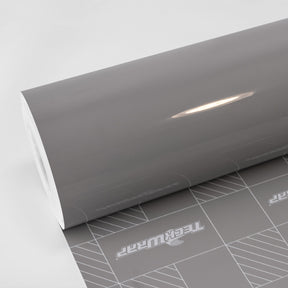 Wild Dove (CG55-HD) Vinyl Wrap by TeckWrap – a high-gloss automotive wrap in a sleek, refined grey shade, shown partially unrolled with a smooth, reflective surface and precision-cut backing paper for easy application.