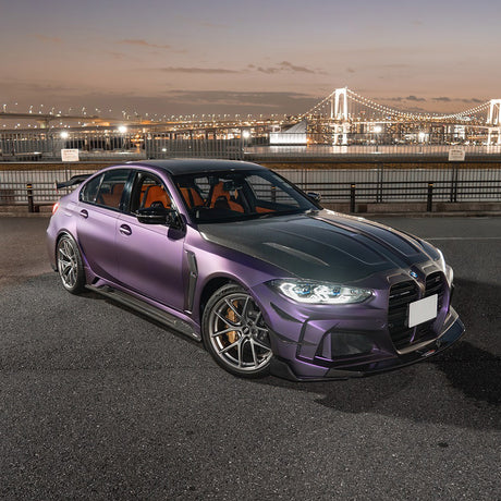 Front-side angle of a BMW wrapped in TeckWrap Satin Venetian Violet (SMT03) vinyl, highlighting the luxurious satin finish against an illuminated cityscape background.