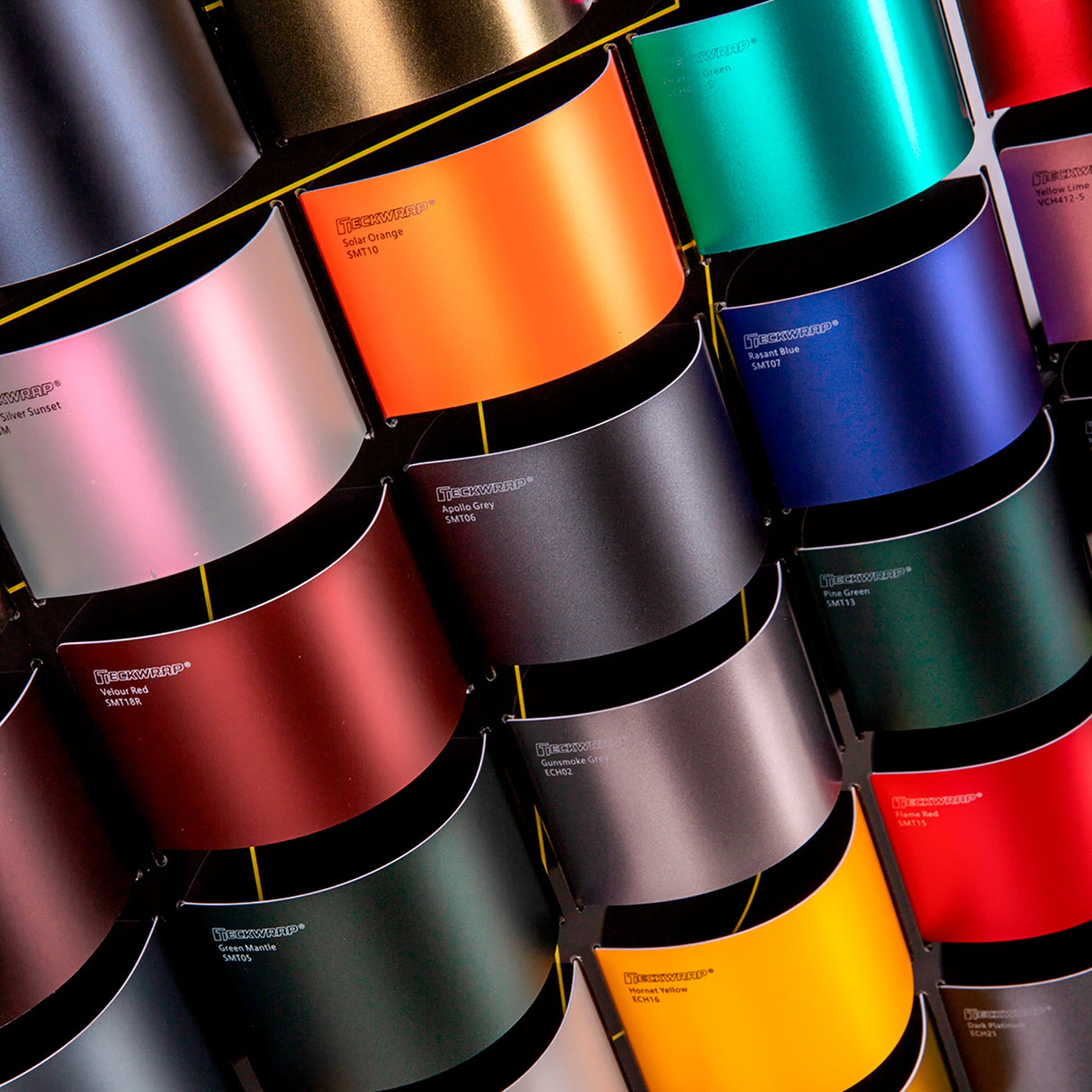 Colorful rolls of vinyl wrap samples with a brand name on a dark background