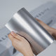 Hands holding a TeckWrap Stellar Silver Metallic PPF sample (CPX406), highlighting its bright glossy silver metallic finish and premium paint protection surface.