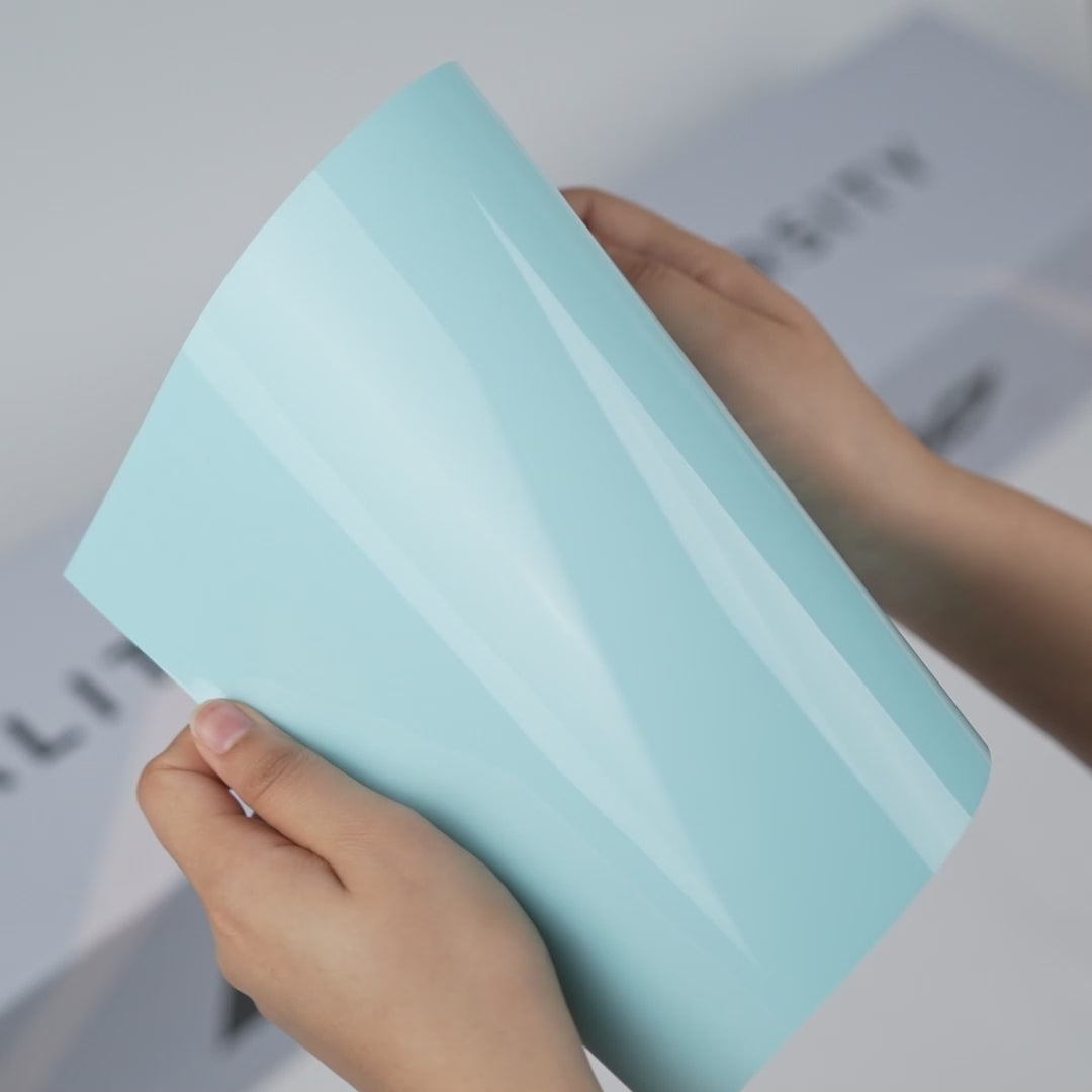 Hands holding a TeckWrap Mint Blue Gloss Color PPF sample (CPX305), showcasing its fresh glossy mint-blue finish and premium paint protection surface.